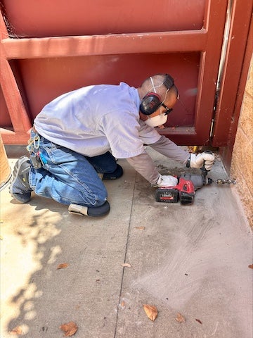  electrician kneeling and drilling a hole in a wall