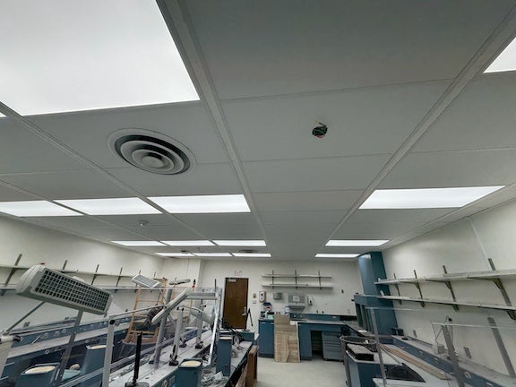 Laboratory with ceiling lights, shelves, and workstations.