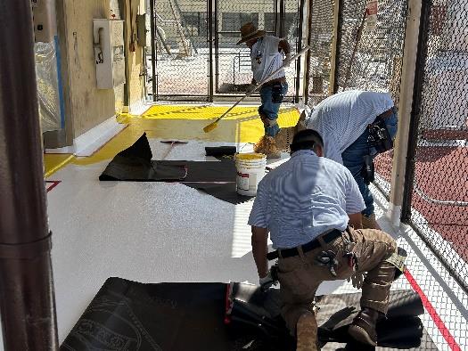 three men working on recoating a roof