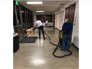 three members of the custodial floor care team cleaning a hallway floor